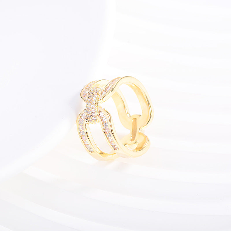 Gold-tone scarf ring standing upright on white folded fabric.