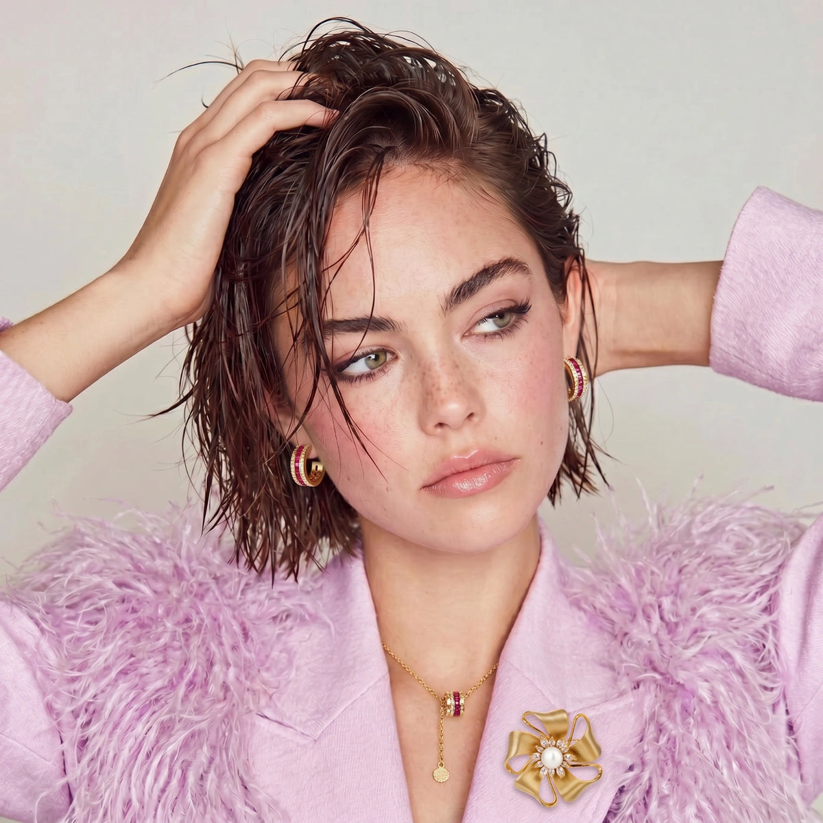 Gold Bloom flower brooch worn on a pale pink top beneath a fluffy purple jacket.