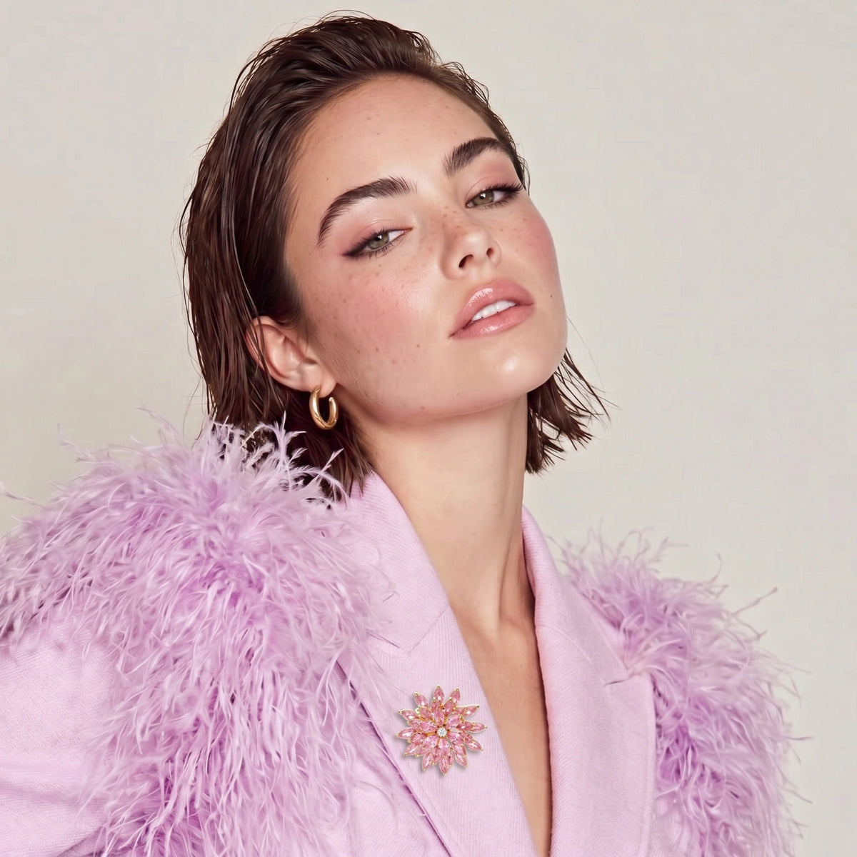 Bloom Burst pink floral brooch worn on a pale pink top beneath a fluffy purple jacket.