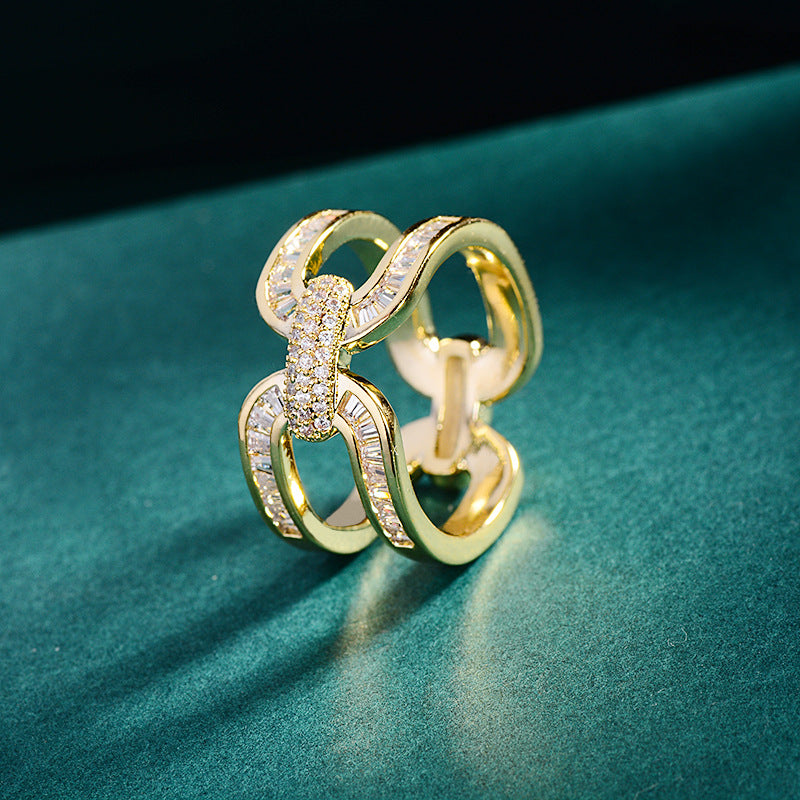 Gold-tone scarf ring with interlocking loops and sparkling accents on dark green fabric.