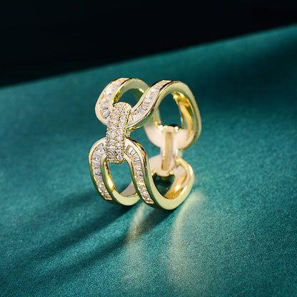 Gold-tone scarf ring with interlocking loops and sparkling accents on dark green fabric.