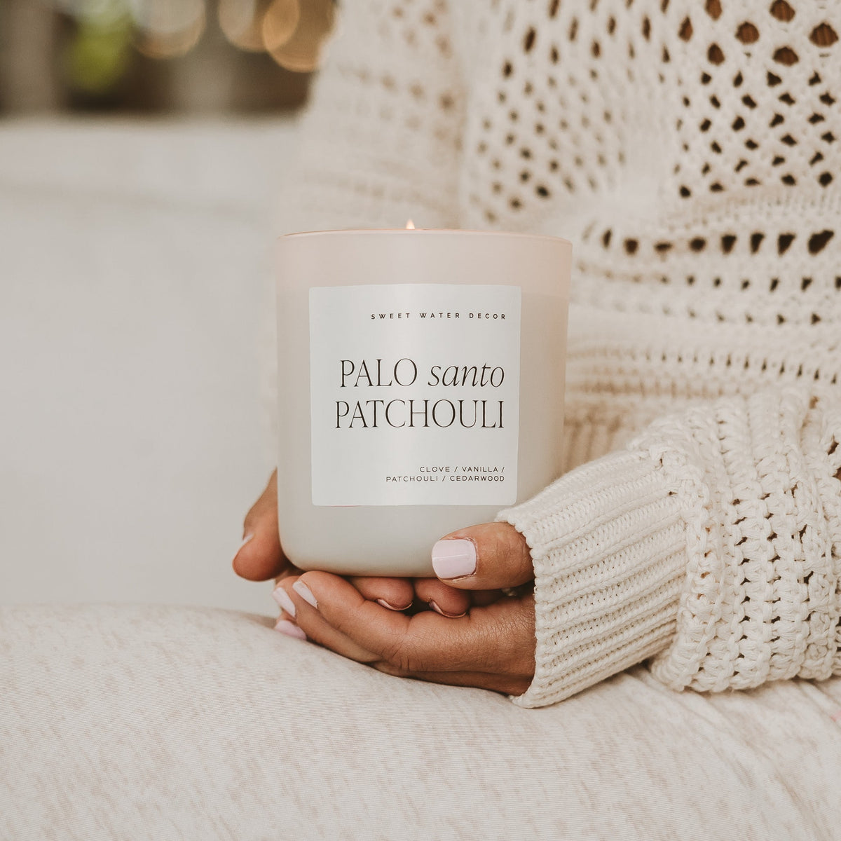 Palo Santo Patchouli candle held by a person wearing a cream knit sweater.