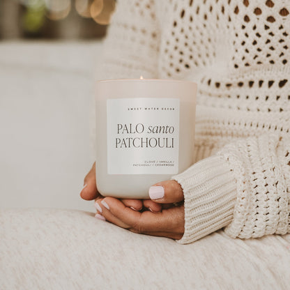 Palo Santo Patchouli candle held by a person wearing a cream knit sweater.