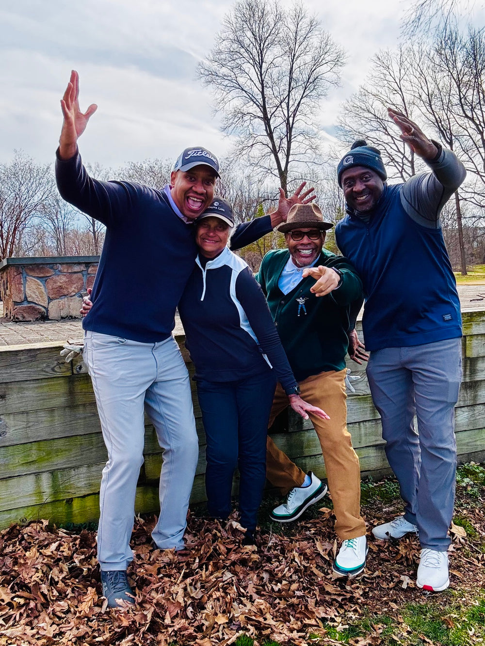 Four friends smiling together outdoors in golf attire