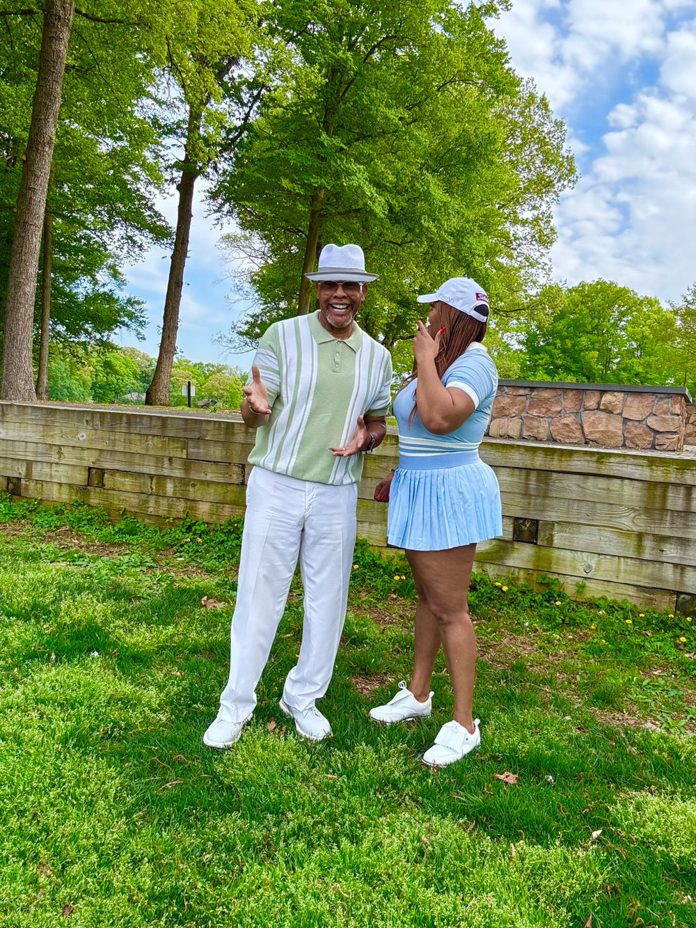 Two people sharing a cheerful moment outdoors in golf attire