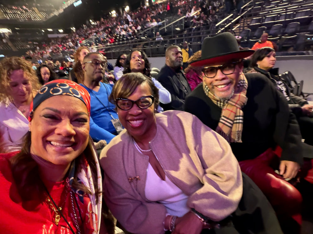 Three smiling friends seated together at an arena event